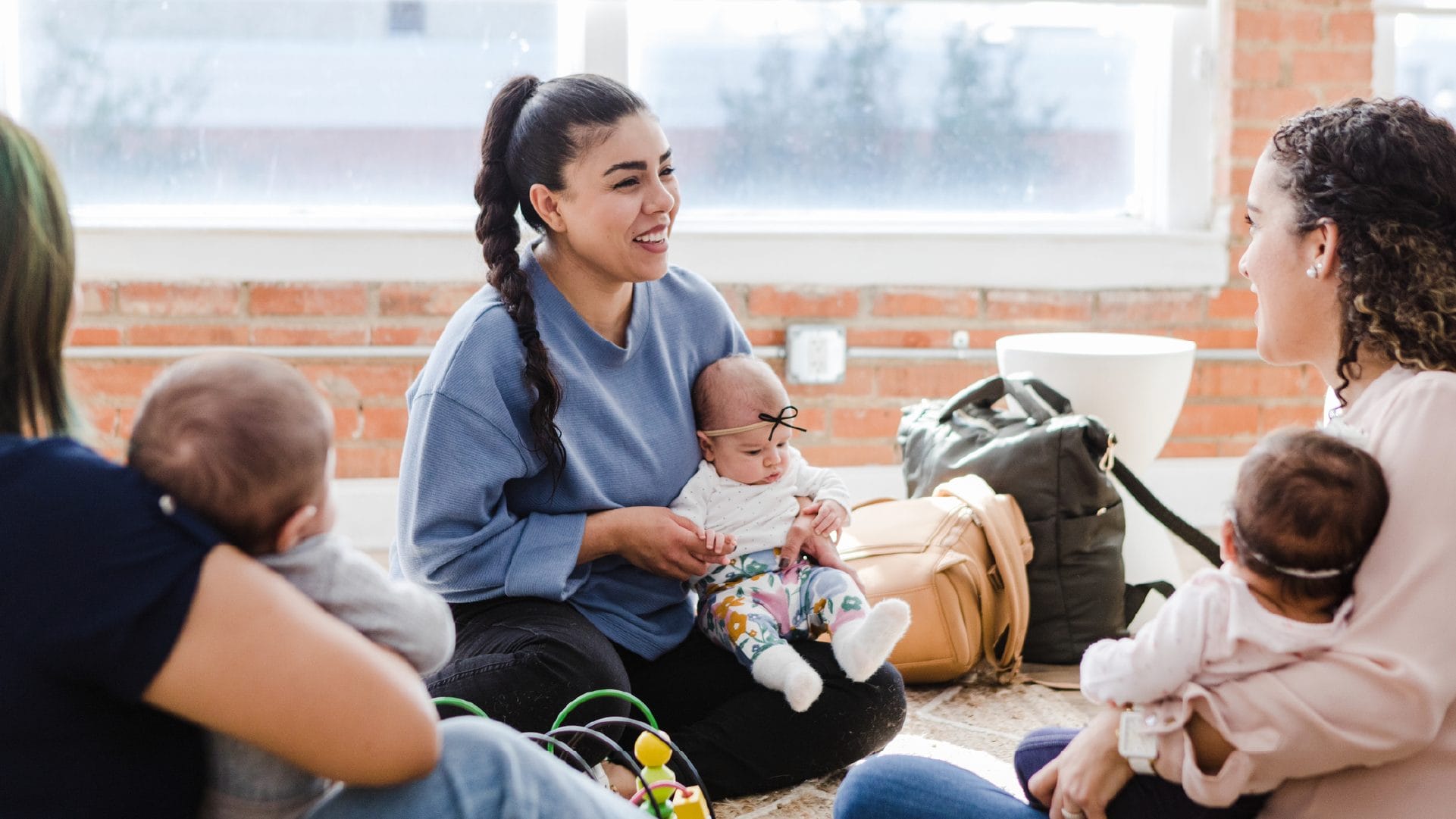 Young adult mother smiles while holding baby at parent support group