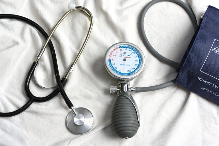 A stethoscope and a sphygmomanometer on a white surface, used for medical examinations and blood pressure measurement.