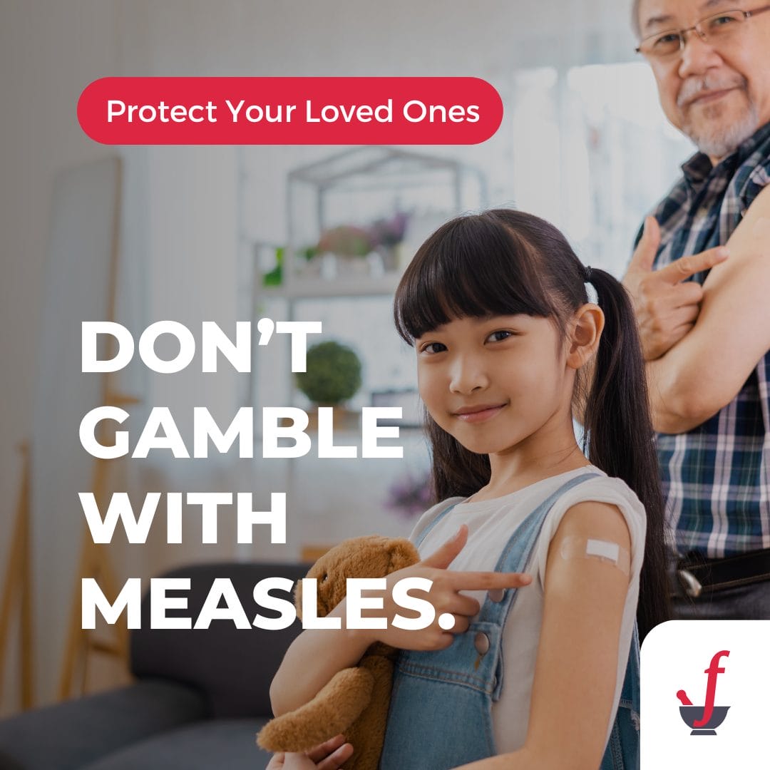 Young girl with a teddy bear points to her vaccination bandage, while an older man smiles in the background.